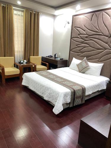 a bedroom with a large bed and a chair at Holiday Hotel in Hai Phong