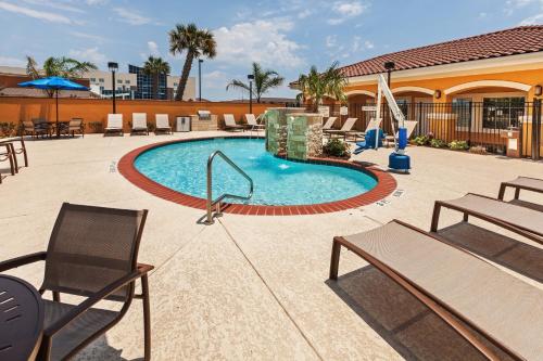 una piscina en un hotel con sillas y mesas en TownePlace Suites by Marriott Corpus Christi, en Corpus Christi