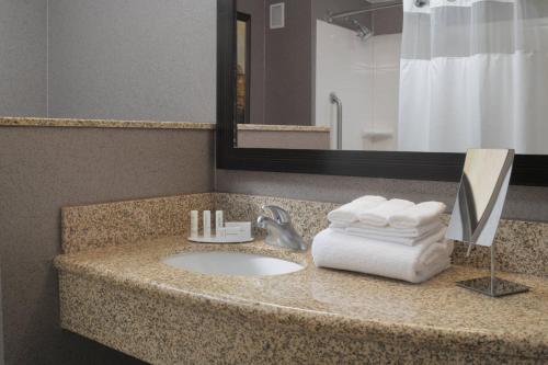 a bathroom with a sink with towels and a mirror at Courtyard by Marriott San Antonio Riverwalk in San Antonio