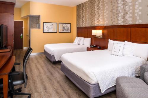 a hotel room with two beds and a couch at Courtyard by Marriott Victorville Hesperia in Hesperia