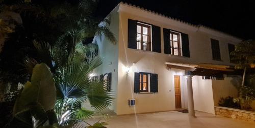 a white house with black windows and a palm tree at *Casa Aguamarina* Villa am Meer in Cala Pi
