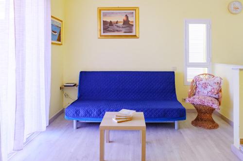 eine blaue Couch in einem Zimmer mit einem Tisch und einem Stuhl in der Unterkunft Casa del sol 2 bedrooms in Morro del Jable