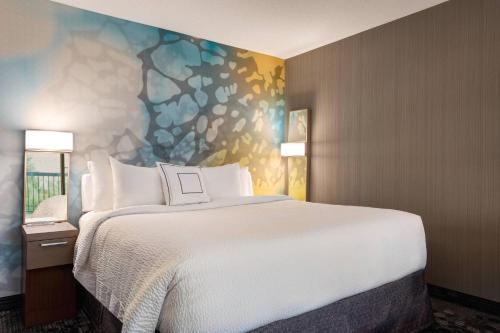 a bedroom with a large bed with a painting on the wall at Courtyard by Marriott Dayton North in Dayton