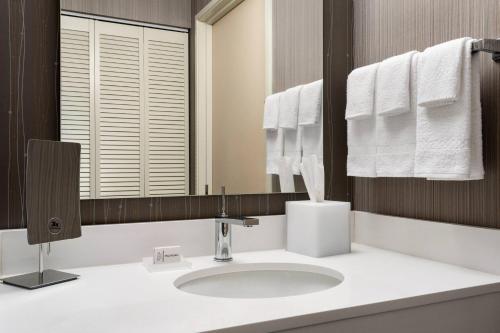 a bathroom with a sink and a mirror and towels at Courtyard by Marriott Dayton North in Dayton