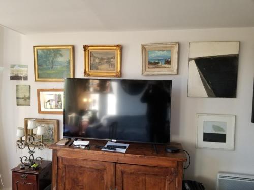 TV de pantalla plana grande en una pared con fotografías en château de Beuzeval, golf de Hougate en Gonneville-sur-Mer
