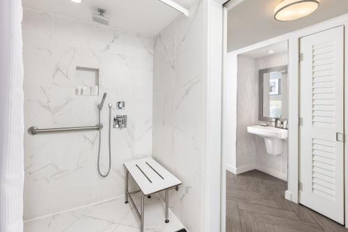 a white bathroom with a shower and a bench at Marriott Stanton South Beach in Miami Beach