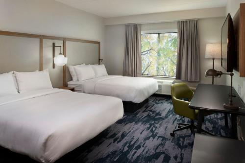 ArlingtonにあるFairfield by Marriott Inn & Suites Memphis Arlingtonのベッド2台、デスク、窓が備わるホテルルームです。