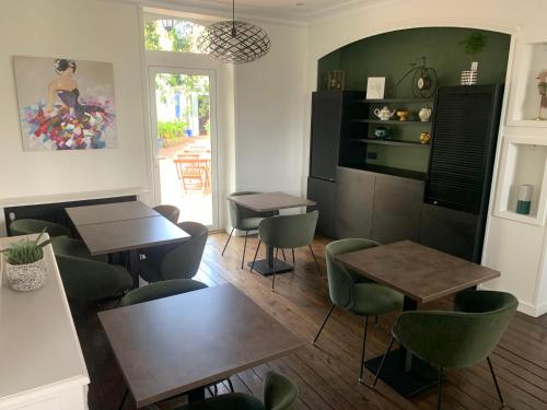 a dining room with tables and green chairs at Hôtel de France in Pléneuf-Val-André