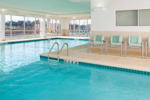 une grande piscine avec des chaises bleues dans un bâtiment dans l'établissement SpringHill Suites by Marriott Macon, à Macon