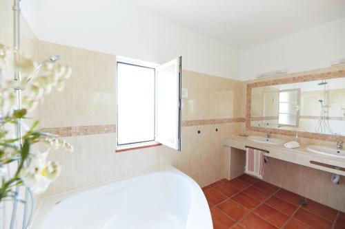 een badkamer met een bad, een wastafel en een raam bij Ocean Whisper in Aljezur