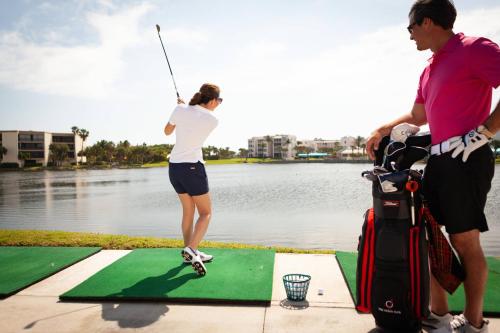 a woman is playing golf next to the water at Marriott Hutchinson Island Beach Resort, Golf & Marina in Stuart
