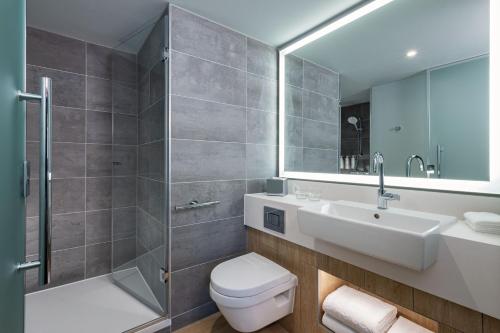 La salle de bains est pourvue de toilettes, d'un lavabo et d'une douche. dans l'établissement Courtyard by Marriott Paris Charles de Gaulle Central Airport, à Roissy-en-France