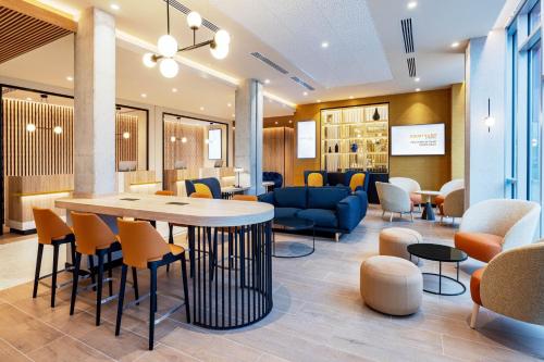 a waiting room with a table and chairs at Courtyard by Marriott Paris Charles de Gaulle Central Airport in Roissy-en-France