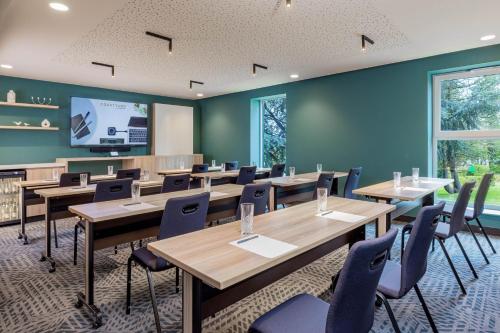 a conference room with tables and chairs and a screen at Courtyard by Marriott Paris Charles de Gaulle Central Airport in Roissy-en-France
