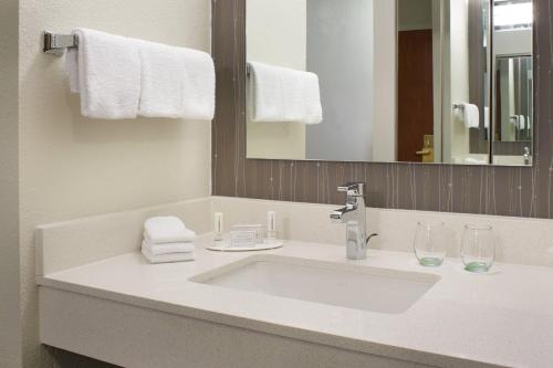 a bathroom with a sink and a mirror and towels at Courtyard Kansas City Overland Park / Convention Center in Overland Park