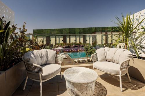 eine Terrasse mit 2 Stühlen, einem Tisch und einem Pool in der Unterkunft Rabat Marriott Hotel in Rabat