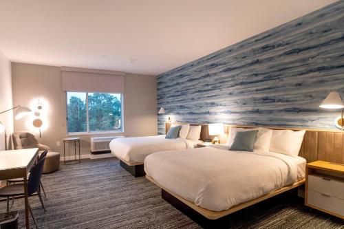 um quarto de hotel com duas camas e uma grande parede de pedra em TownePlace Suites by Marriott Conroe em Conroe