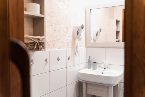 a white bathroom with a sink and a mirror at Karczma Zacisze in Krutyń