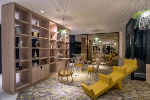 a store with yellow chairs and tables in a room at The Jangle Hotel - Paris - Charles de Gaulle - Airport in Le Mesnil-Amelot