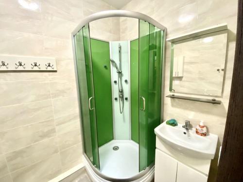 y baño con ducha verde y lavabo. en 26 Perlyna Arcadia apartment, en Odessa