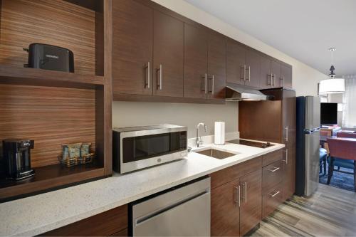 a kitchen with wooden cabinets and a microwave at TownePlace Suites by Marriott Grand Rapids Wyoming in Wyoming