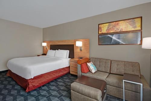 Habitación de hotel con cama y sofá en TownePlace Suites by Marriott Grand Rapids Wyoming en Wyoming