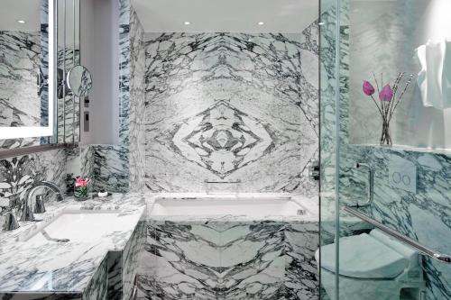 uma casa de banho com uma banheira e uma parede em mármore em London Marriott Hotel Park Lane em Londres