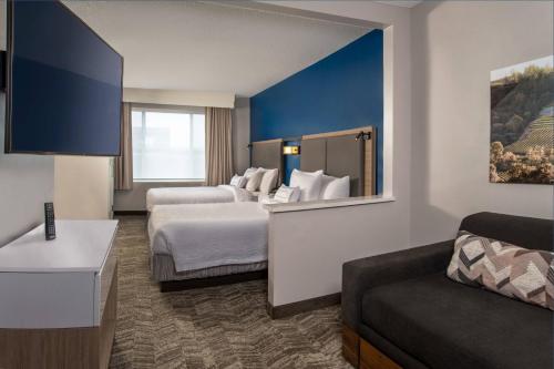 a hotel room with two beds and a couch at SpringHill Suites Herndon Reston in Herndon