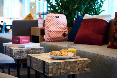 a table with a bowl of food and a glass of orange juice at Moxy Paris Charles de Gaulle Airport in Roissy-en-France