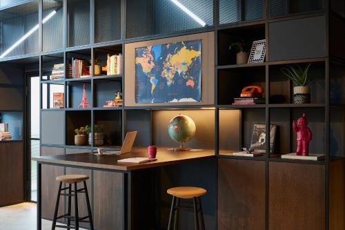 a library with a desk and stools in a room at Moxy Paris Charles de Gaulle Airport in Roissy-en-France