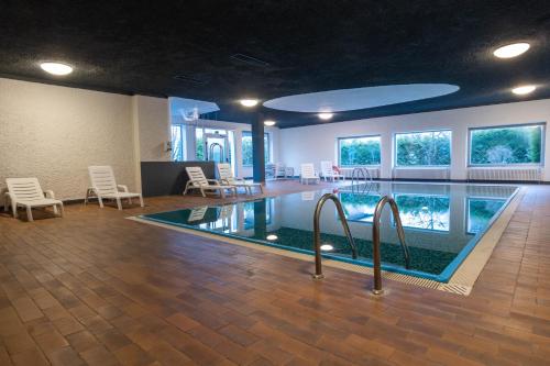 a pool in a room with chairs and a swimming pool at Hotel Regina del Bosco in Ronzone