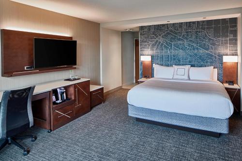 a hotel room with a bed and a desk and a television at Courtyard by Marriott Minneapolis West in Saint Louis Park