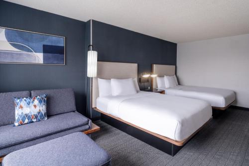 a hotel room with two beds and a couch at Courtyard Salt Lake City Airport in Salt Lake City