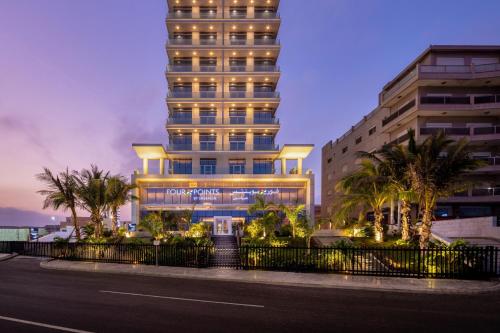un grand bâtiment avec des palmiers en face d'une rue dans l'établissement Four Points by Sheraton Jeddah Corniche, à Djeddah