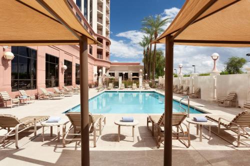 a swimming pool at a hotel with chairs and a table at Marriott Phoenix Airport in Phoenix