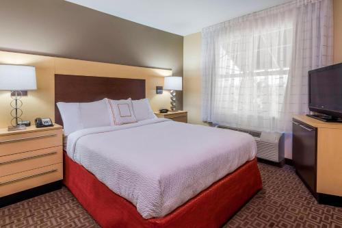 a hotel room with a bed and a flat screen tv at TownePlace Suites Tampa Westshore/Airport in Tampa