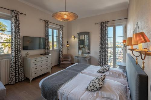 a bedroom with a bed and a tv and windows at Hotel Restaurant de la Tour in Sanary-sur-Mer