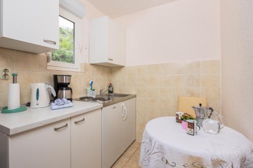 a kitchen with white cabinets and a table in it at Panoramare Komplex Vesna in Zagorje