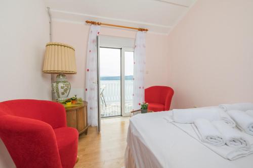 a bedroom with a bed and two red chairs at Panoramare Komplex Vesna in Zagorje