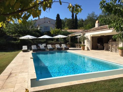 une piscine avec chaises et parasols dans une cour dans l'établissement Villa Milefleure, à Grimaud