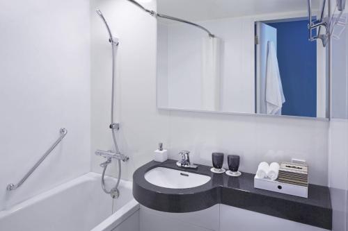 a white bathroom with a sink and a mirror at Courtyard by Marriott Tokyo Station in Tokyo