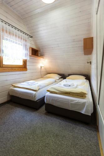 a room with two beds in a room with a window at Angela Domki i Pokoje in Pobierowo
