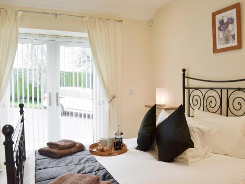 um quarto com uma cama e uma porta de vidro com uma varanda em Hameish Holiday Cottage em Kirkcudbright