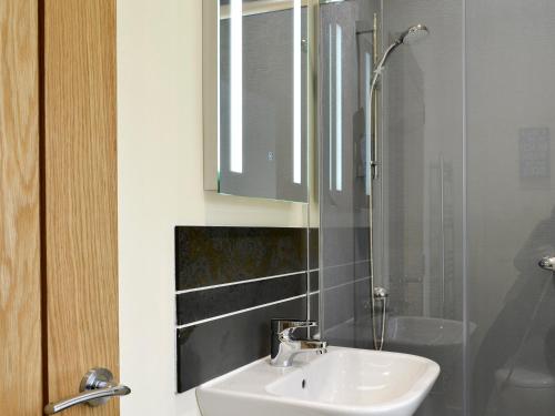 a bathroom with a sink and a shower at Hameish Holiday Cottage in Kirkcudbright