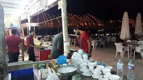 a group of people standing around a table with mugs at Villa with Roof, Private Garden and Backyard in North Coast - Families Only فيلا مستقلة الساحل الشمالي - عائلات فقط in Dawwār Abū Maḩrūs