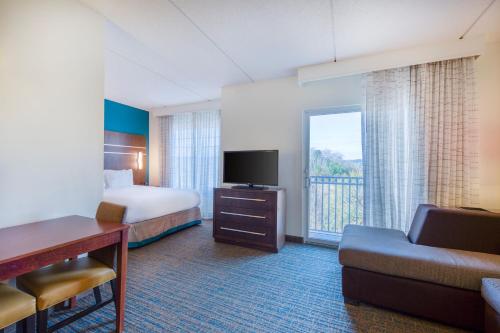 a hotel room with a bed and a couch and a television at Residence Inn by Marriott Raleigh Crabtree Valley in Raleigh