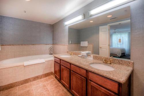 a bathroom with two sinks and a tub and a mirror at Residence Inn by Marriott Raleigh Crabtree Valley in Raleigh