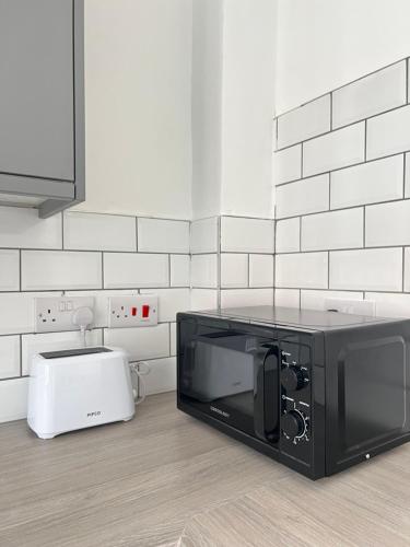 a microwave oven sitting on a kitchen floor at Burleigh House - 3 Bed House in Leicester