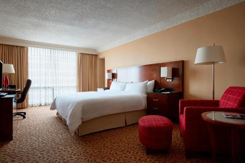 Stamford Marriott Hotel & Spa في ستامفورد: غرفة فندقية بسرير كبير وكرسي احمر