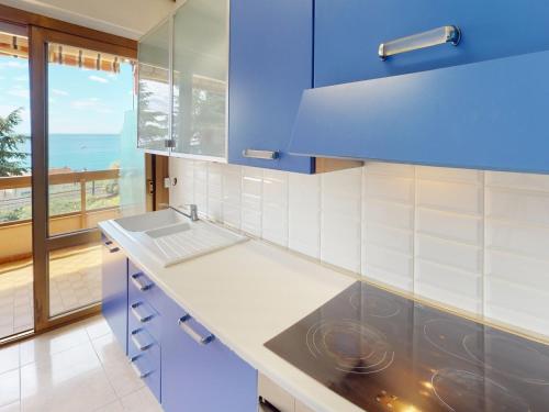 une cuisine avec des placards bleus et une vue sur l'océan dans l'établissement Joli studio avec terrasse et garage privé à Menton - FR-1-196-296, à Menton